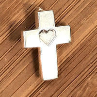 small cross around 20mm high and 14mm across. At the top there is a small u ring to which a jump ring is attached. A shape of a heart is engraved in the intersection between the vertical and horizontal posts. The outline of the cross is approsimately 3mm wide and 1mm thick. The finish is shiny. The cross is shown on a piece of wood.